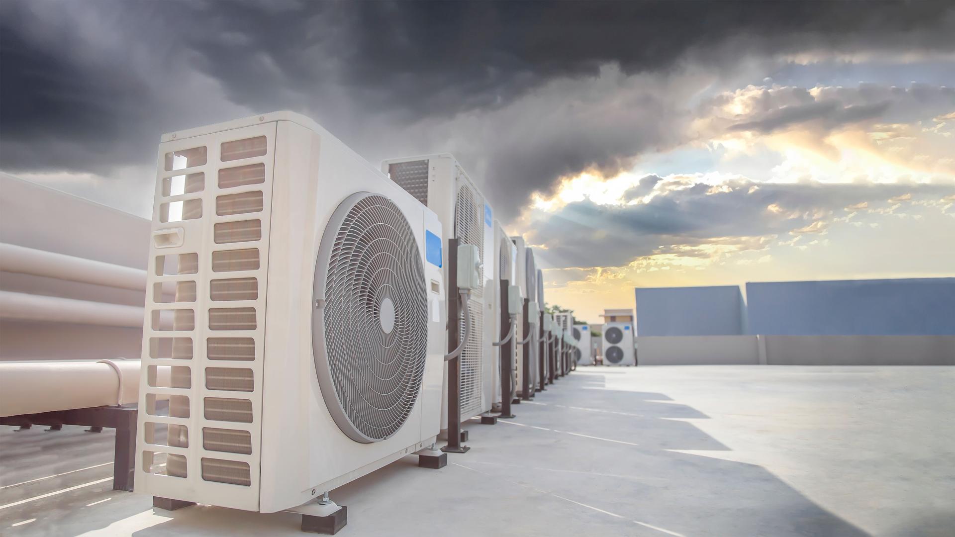 Air conditioning (HVAC) on the roof of an industrial building with blue sky and clouds.
