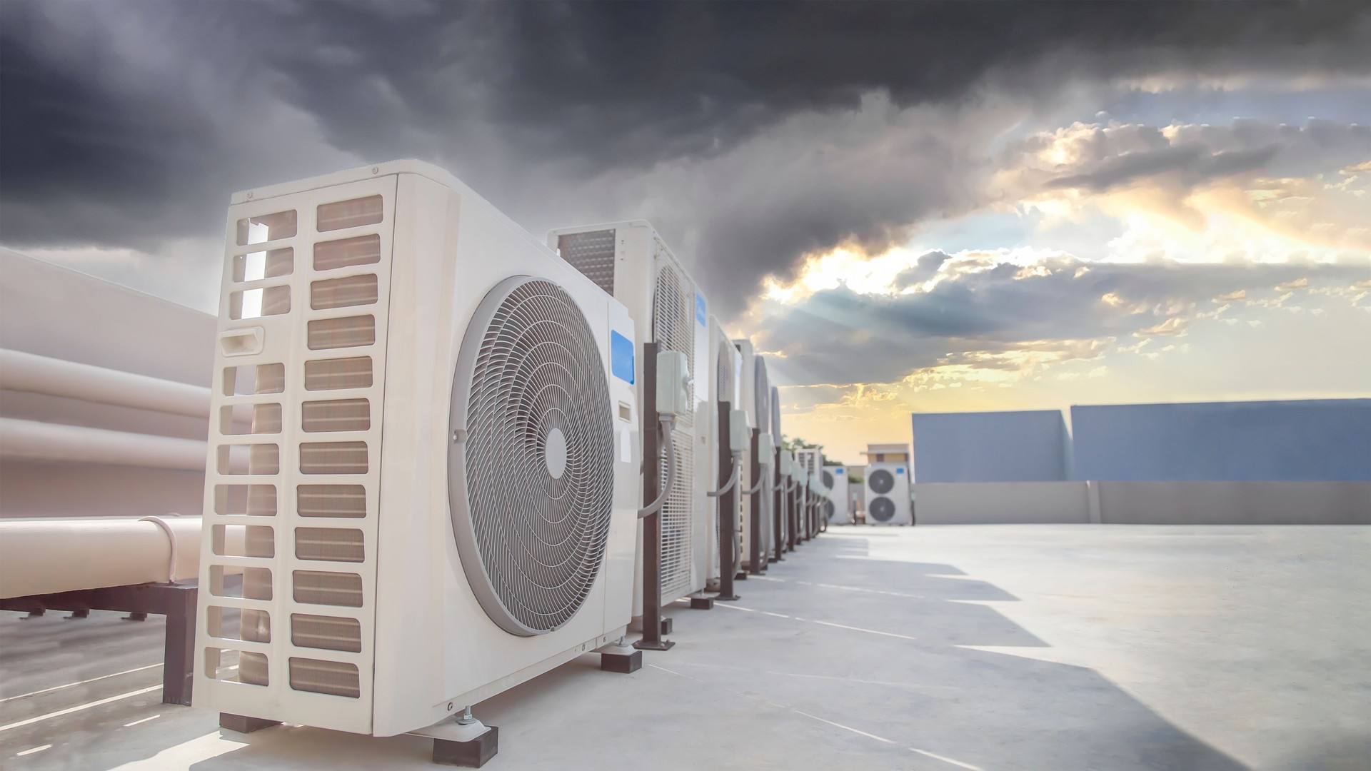 Air conditioning (HVAC) on the roof of an industrial building with blue sky and clouds.